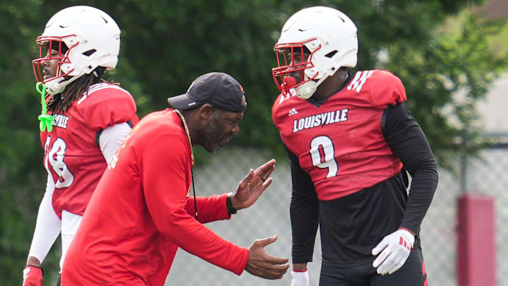 Louisville Cardinals Ron English, co-Defensive Coordinator/Secondary, pushes linebacker Antonio Watts
