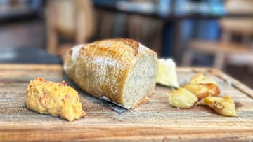 A crusty loaf of fresh sourdough bread is served with roasted garlic and pimento cheese at Colab Kitchen restaurant in Stuart.