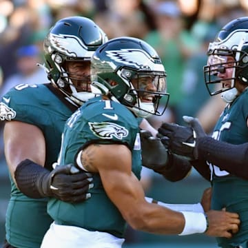 Lane Johnson and Jordan Mailata help Jalen Hurts celebrate.
