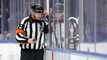 Mar 24, 2025; Elmont, New York, USA; NHL referee Wes McCauley (4) puts on a headset for a video review of a disallowed Islanders goal during the third period between the New York Islanders and the Columbus Blue Jackets at UBS Arena. Mandatory Credit: Brad Penner-Imagn Images
