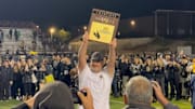 Newbury Park football coach Joe Smigiel raises the CIF championship plaque after beating Murrieta Valley 31-28 on Saturday, November 30, 2024.