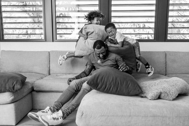 John Wall reacts as both of his sons jump on him with pillows during a play fight on the couch.