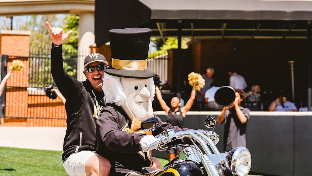 Head football coach Jake Dickert rides out on the motercycle with the Demon Deacon 