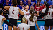 The Huskers run towards Andi Jackson (middle) after her kill. 