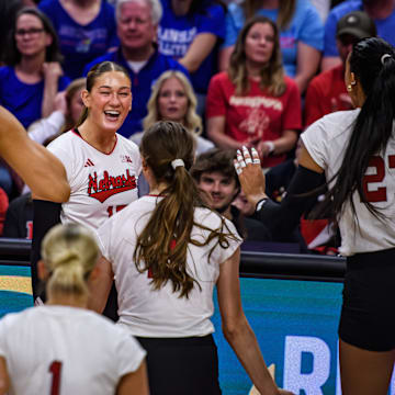 The Huskers run towards Andi Jackson (middle) after her kill. 