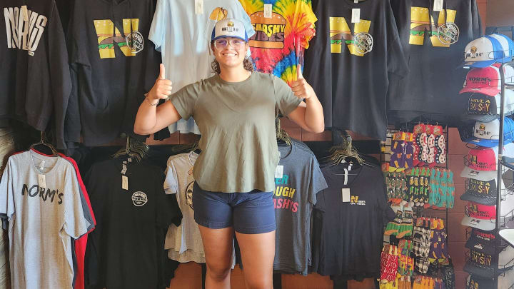 Nebraska volleyball middle blocker Rebekah Allick poses with merch at Norm's on 48th where she will run the register during an upcoming lunch rush.