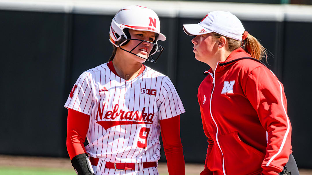 Hannah Camenzind (9) chats with assistant coach Olivia Ferrell after a single. 