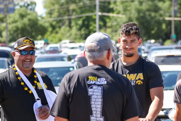 Iowa coach Kirk Ferentz talks with 2025 recruiting target Iose Epenesa (right) and his father, Epenesa Epenesa, practice on A