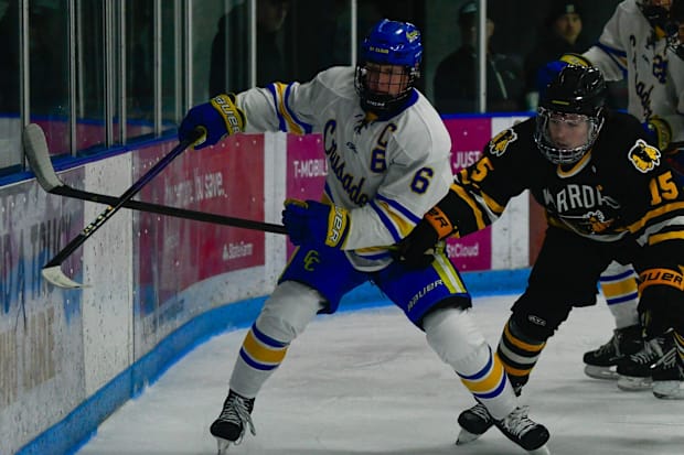 St. Cloud Cathedral hockey senior John Hirschfeld fights to keep possession of the puck against Warroad's Taven James in the 