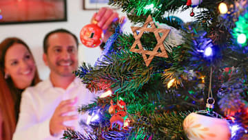 Two people decorating a Christmas tree during the holidays
