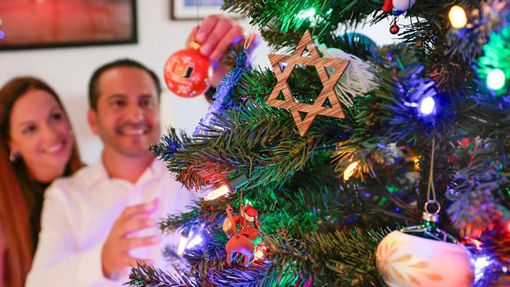 Two people decorating a Christmas tree during the holidays