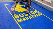 Hopkinton resident Joy Donohue photographs Peter Thibeault of New Hampshire based Mission Turf Services painting the 129th Boston Marathon start line in Hopkinton, April 16, 2025. Donohue will be running the Marathon to raise funds for the Hopkintion Arts Center.