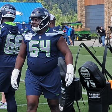 Seahawks rookie Christian Haynes listens to instructions from coach Scott Huff prior to a sled blocking drill at OTAs.