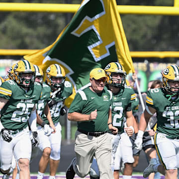 St. Edward takes the field before a football game in 2023, led by head coach Tom Lombardo. 