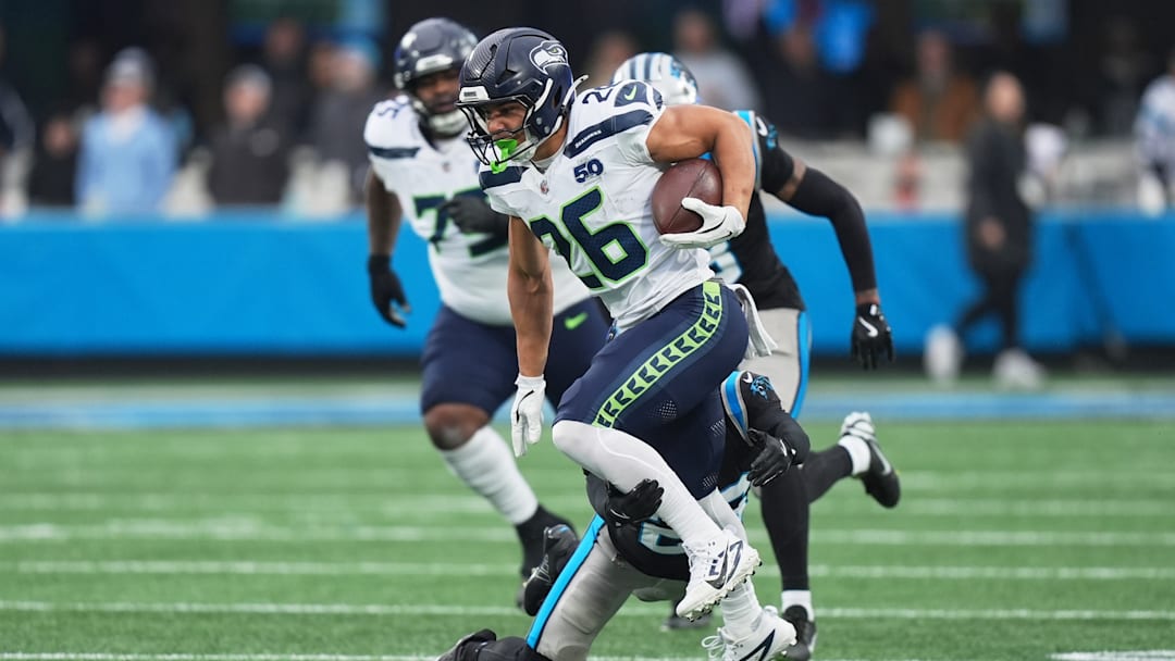 Dec 28, 2025; Charlotte, North Carolina, USA; Seattle Seahawks running back Zach Charbonnet (26) runs the ball against Carolina Panthers cornerback Chau Smith-Wade (26) (obscured) during the first quarter at Bank of America Stadium. 