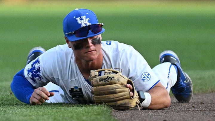 Jun 17, 2024; Omaha, NE, USA;  Kentucky Wildcats shortstop Grant Smith (12) dives for a ground ball against the Texas A&M Aggies during the fifth inning at Charles Schwab Field Omaha. Mandatory Credit: Steven Branscombe-Imagn Images