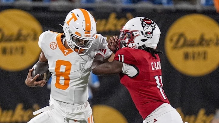 Sep 7, 2024; Charlotte, North Carolina, USA; Tennessee Volunteers quarterback Nico Iamaleava (8) tries to fend off North Carolina State Wolfpack safety Ja'Had Carter (11) during the first quarter at the Dukes Mayo Classic at Bank of America Stadium. Mandatory Credit: Jim Dedmon-Imagn Images