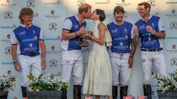 Duchess of Sussex Meghan Markle and Prince Harry, Duke of Sussex share a kiss after she presented him and his team with the champions trophy after a polo play at Grand Champions Polo in Wellington, Fla.