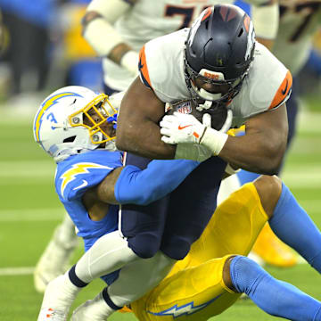 Dec 19, 2024; Inglewood, California, USA; Denver Broncos running back Audric Estime (23) is stopped by Los Angeles Chargers safety Derwin James Jr. (3) in the first half at SoFi Stadium. 