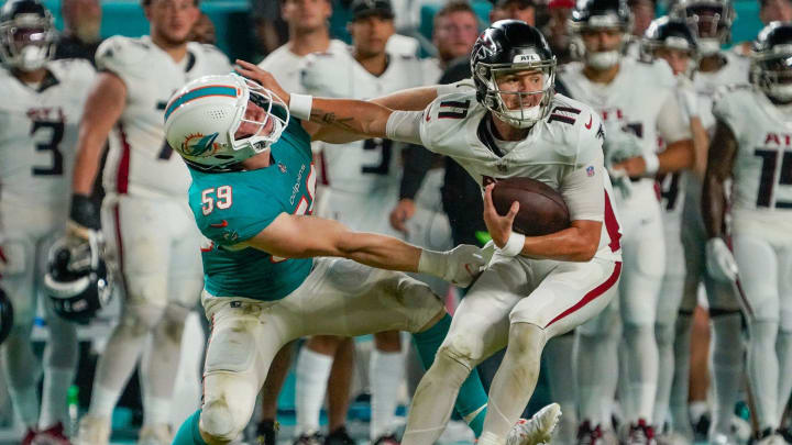 Miami Dolphins linebacker Mike Rose (59) is stiff armed by Atlanta Falcons quarterback Logan Woodside (11) during the fourth quarter of a preseason game at Hard Rock Stadium on Friday, August 11, 2023, in Miami Gardens, FL.