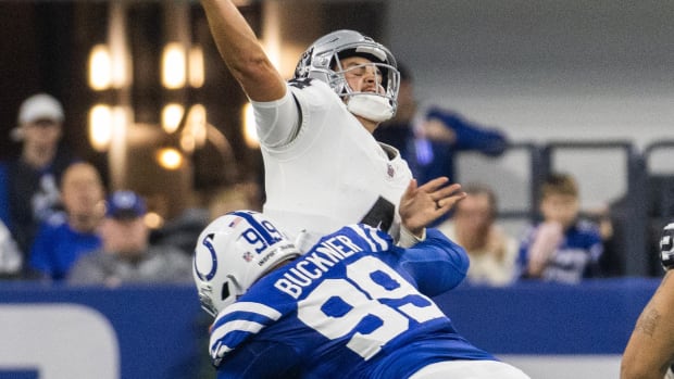 Colts defensive tackle DeForest Buckner (blue jersey;white pants/helmet) hits the opposing quarterback to disrupt the pass.