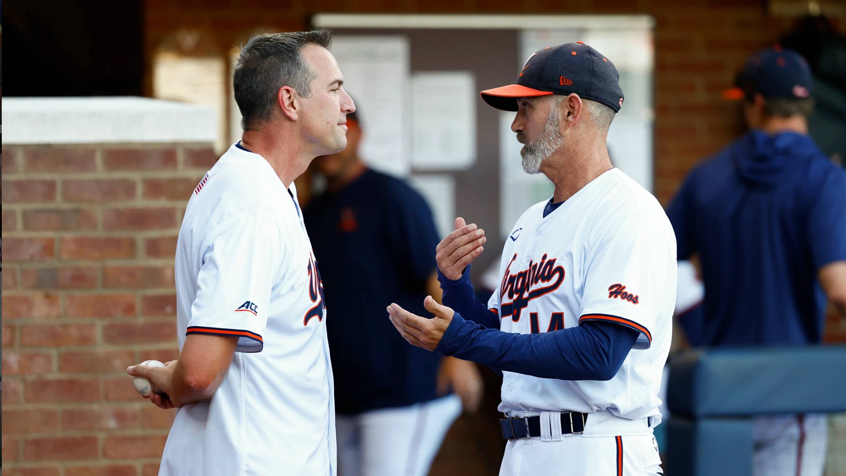 Virginia women's basketball Coach Aaron Roussell (L) and baseball Coach Chris Pollard (R) talk as Roussell prepares to throw the ceremonial first pitch April 16 at Disharoon Park.