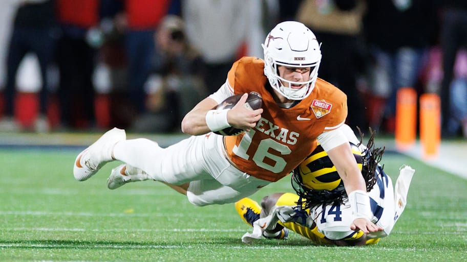 Texas Longhorns quarterback Arch Manning reaches with the ball for a first down.