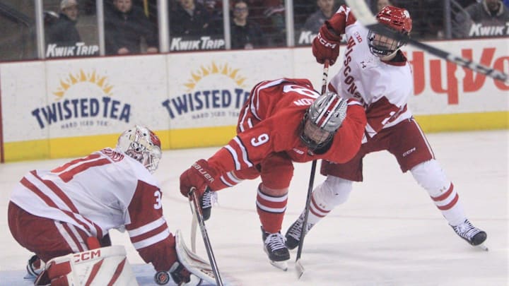 Ohio State's Riley Thompson keeps his balance after taking a shot against Wisconsin' goaltender Daniel Hauser and Luke Osburn in a Big Ten quarterfinal at the Kohl Center in Madison, Wis. on March 11. 2026.
