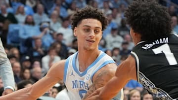 Dec 7, 2025; Chapel Hill, North Carolina, USA;  North Carolina Tar Heels guard Kyan Evans (0) passes the ball to forward Caleb Wilson (8) as Georgetown Hoyas forward Isaiah Abraham (7) defends in the second half at Dean E. Smith Center. Mandatory Credit: Bob Donnan-Imagn Images