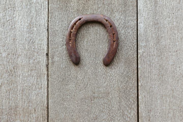 rusty horseshoe hanging upside-down on a wall
