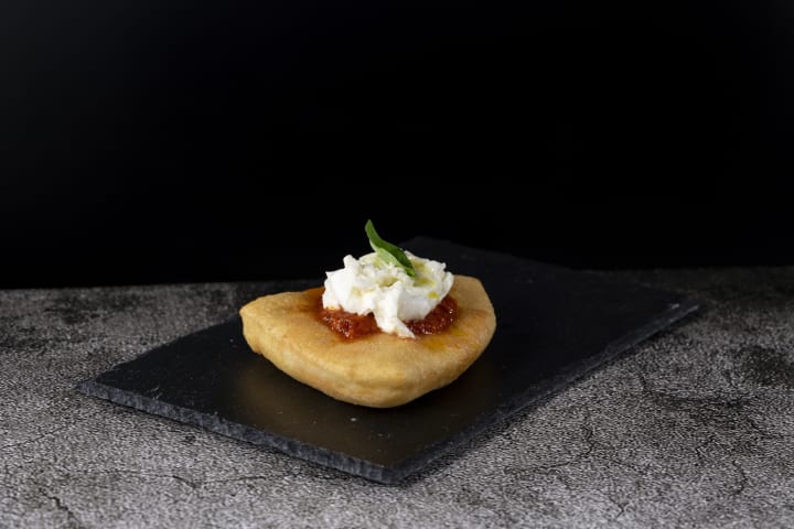 Pizza Margherita fritta (fried) on black stone cutting board, Italy