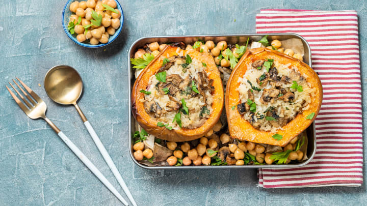 Squash stuffed with rice and mushroom on baking sheet with chickpeas.