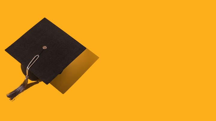 Black graduation cap with gray tassel on yellow background.