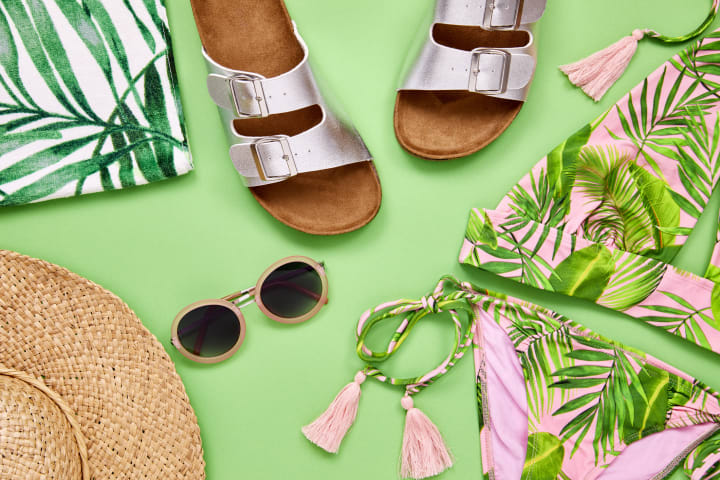 Overhead shot of summer vacation accessories on green background. 