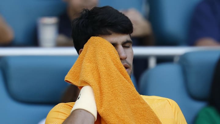 Carlos Alcaraz wipes his face in his player's chair