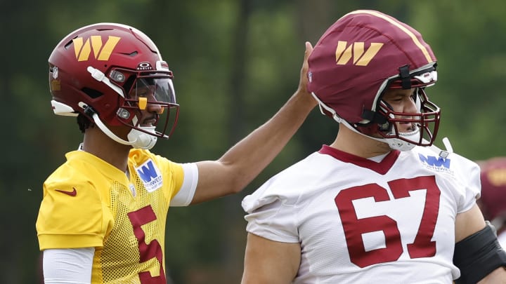 Jul 25, 2024; Ashburn, VA, USA; Washington Commanders quarterback Jayden Daniels (5) taps the helmet of Commanders guard Nick Allegretti (67) during day two of Commanders training camp at OrthoVirginia Training Center at Commanders Park. Mandatory Credit: Geoff Burke-USA TODAY Sports