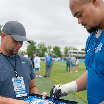 Detroit Lions OL Giovanni Manu signs an autograph after practice at team's Performance Center