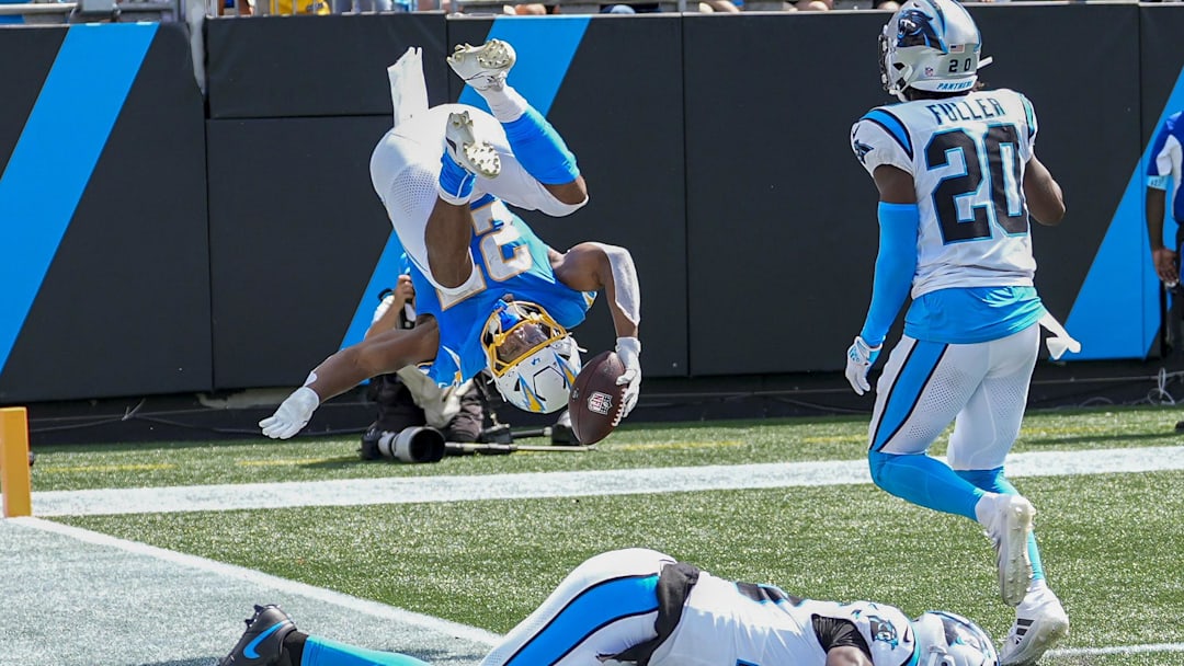 Sep 15, 2024; Charlotte, North Carolina, USA; Los Angeles Chargers running back J.K. Dobbins (27) flips into the end zone ahead of Carolina Panthers safety Jordan Fuller (20) and safety Xavier Woods (25) for a touchdown against the Carolina Panthers during the second quarter at Bank of America Stadium. Mandatory Credit: Jim Dedmon-Imagn Images