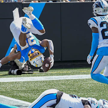 Sep 15, 2024; Charlotte, North Carolina, USA; Los Angeles Chargers running back J.K. Dobbins (27) flips into the end zone ahead of Carolina Panthers safety Jordan Fuller (20) and safety Xavier Woods (25) for a touchdown against the Carolina Panthers during the second quarter at Bank of America Stadium. Mandatory Credit: Jim Dedmon-Imagn Images