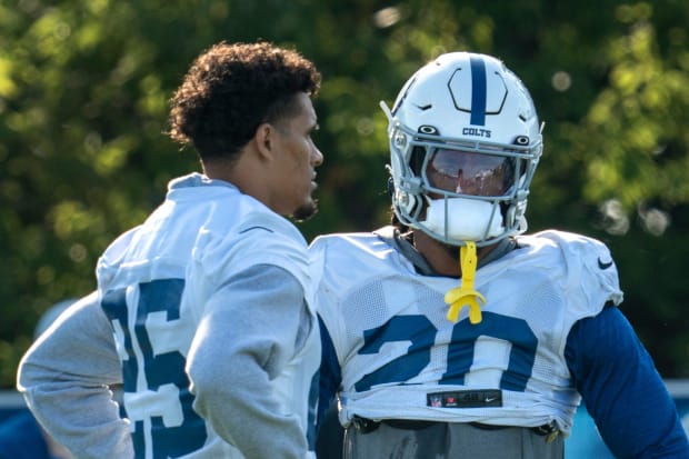 Football players Nick Cross and Rodney Thomas II chat between plays in white jerseys.