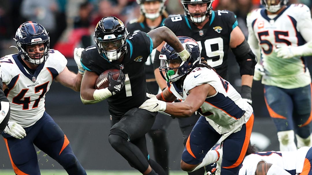 Oct 30, 2022; London, United Kingdom, Jacksonville Jaguars running back Travis Etienne Jr. (1) breaks a tackle from Denver Broncos linebacker Nik Bonitto (42) in the fourth quarter during an NFL International Series game at Wembley Stadium. Mandatory Credit: Nathan Ray Seebeck-Imagn Images