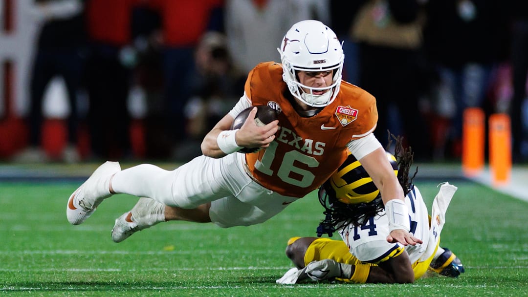 Dec 31, 2025; Orlando, FL, USA; Texas Longhorns quarterback Arch Manning (16) dives forward over Michigan Wolverines defensive back Jordan Young (14) during the second half at Camping World Stadium. Mandatory Credit: Matt Pendleton-Imagn Images
