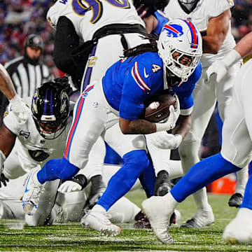 Buffalo Bills running back James Cook, carrying the ball, keeps low as teammate Buffalo Bills offensive tackle Spencer Brown blocks opening a spot for him during first half action at the Buffalo Bills divisional game against the Baltimore Ravens at Highmark Stadium in Orchard Park on Jan. 19, 2025.