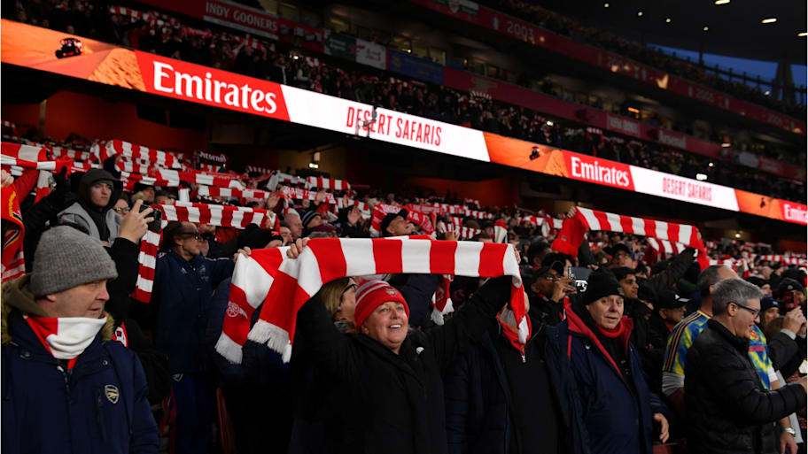 Arsenal’s supporters holding scarves aloft at Emirates Stadium.