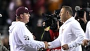 Nov 30, 2024; College Station, Texas, USA; Texas A&M Aggies head coach Mike Elko, left, shakes hands with Texas Longhorns head coach Steve Sarkisian after the game. The Longhorns defeated the Aggies 17-7. at Kyle Field. Mandatory Credit: Maria Lysaker-Imagn Images 