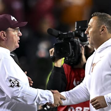 Texas A&M Aggies head coach Mike Elko, left, shakes hands with Texas Longhorns head coach Steve Sarkisian