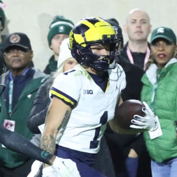 ]Michigan Wolverines wide receiver Roman Wilson (1) runs by Michigan State Spartans defensive back Jaden Mangham (1) for a touchdown during first-half action at Spartan Stadium in East Lansing on Saturday, Oct. 21, 2023.