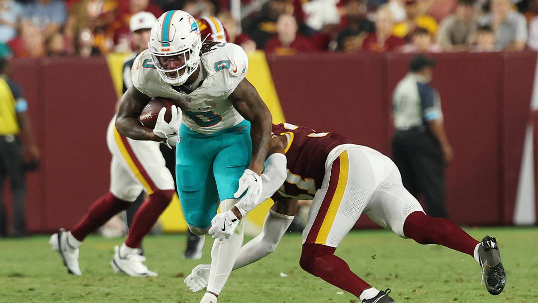 Miami Dolphins running back Ollie Gordon II (0) runs with the ball as Washington Commanders cornerback Car'lin Vigers (37) makes a tackle during the second half at Northwest Stadium. Miami Dolphins running back Ollie Gordon II (0) runs with the ball as Washington Commanders cornerback Car'lin Vigers (37) makes a tackle during the second half at Northwest Stadium.