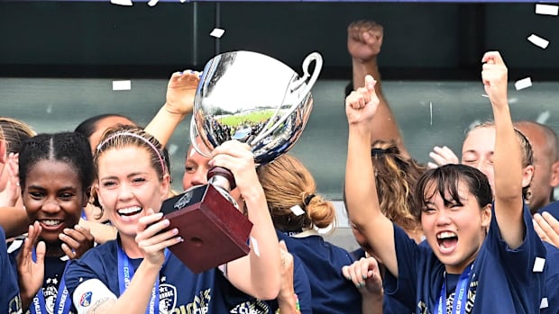 The North Carolina Courage holds the 2022 Challenge Cup trophy aloft.