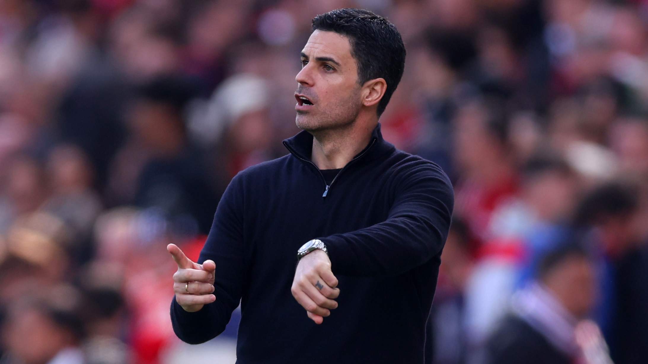 Mikel Arteta pointing at his watch.